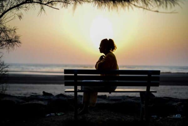 Making Sense of Menopause A woman sits on a bench at sunset.